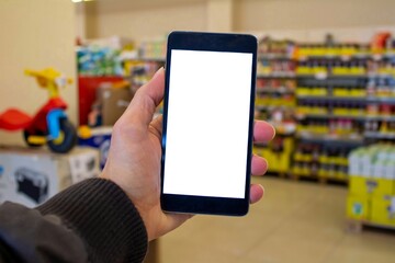 Man hand holding blank white screen mobile phone in the supermarket. Mockup image.