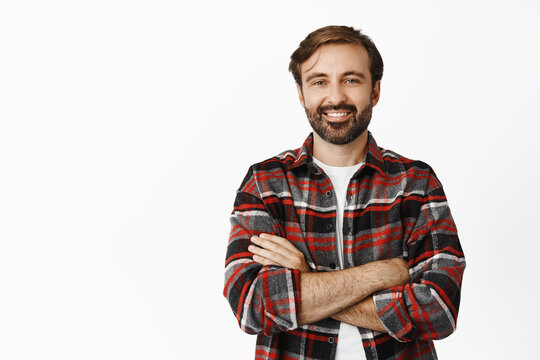 Image of confident man with long beard, cross arms on his chest, real professional, standing in checked shirt over white background