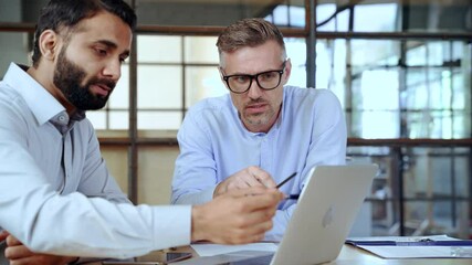 Two diverse business men discussing financial market data using laptop and digital tablet. Financial advisor broker manager consulting investor client about digital investment at office meeting. - Powered by Adobe