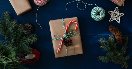 Fototapeta na wymiar wrapping of Christmas gifts in eco-style craft paper and natural materials, fir branches on a blue wooden background.