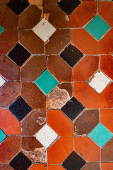 Very old Andalusian Arabic style ceramic tile pattern with geometric shapes and red, orange, green and white colors.