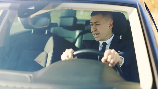 Angry mature man sitting in car and pounding with hands on steering wheel. Business man driving vehicle with negative emotions. Problems, traffic, hurry concept