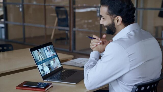 Indian leader manager leading videoconference with diverse team business people having digital group video call conference working in office at online virtual meeting on pc computer. Over shoulder