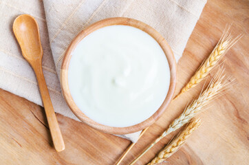 Greek yogurt in a wooden bowl and dry barley.