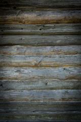 Fototapeta premium Wooden logs of an old house. Close-up. Weathered natural gray wood texture. Background. vertical photo.