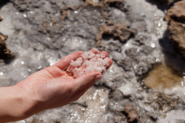 Natural frozen sea salt in the girl's hand. Backgrounds and texture on the seashore in stone deposits flooded with water and the remains of sea salt frozen in time. Close-up. Macro
