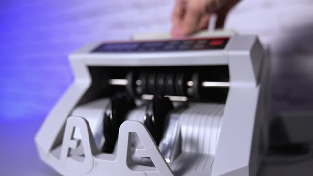 Electronic machine counting hundred dollar bills. Modern automatic equipment for counting paper currency. Money counting machine for banking and commercial activity. Slow motion.