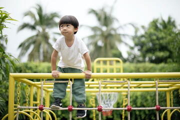 Little asian boy climbing on the playground
