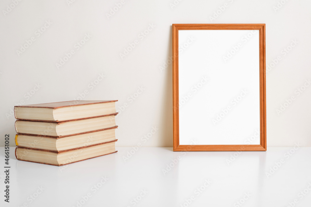 Poster vertical portrait frame mock up. wooden picture frame template with empty space, books on table indo