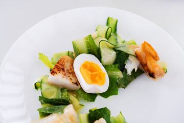 A light dish of fried fish, cucumbers and half an egg. A delicious recipe for a quick meal. Close-up