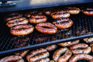 There are many fried sausages on the grill. Cooking food on professional equipment in the restaurant. Close-up