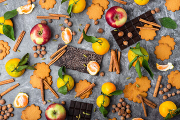 Assortment of holiday season treats scattered over grey background, top view