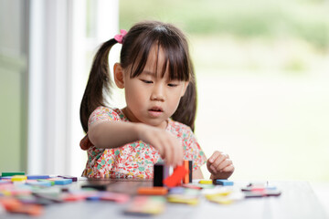 young girl playing domino blocks at home