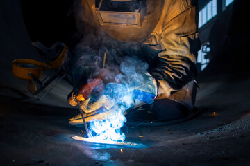 MMA welding. A welder welds large diameter pipes with manual electric arc welding.