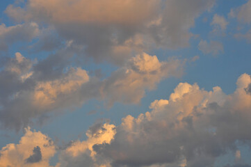 White clouds, illuminated by the sun, in a blue sky