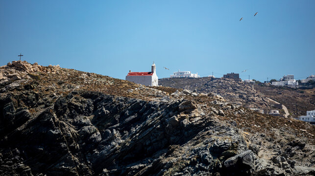 Small old chapel with red roof, Greek Church on the rocky hill, blue sky. Mykonos island, Greece