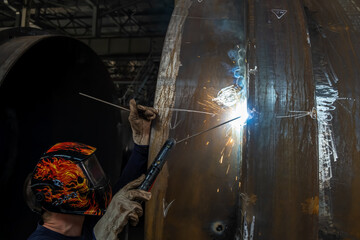 MMA welding. A welder welds large diameter pipes with manual electric arc welding.