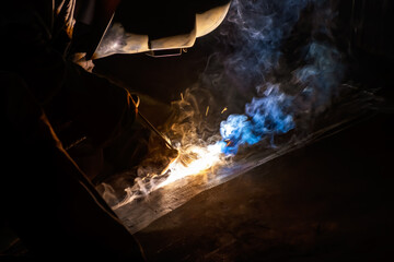 MMA welding. A welder welds large diameter pipes with manual electric arc welding.