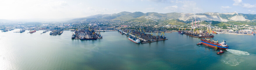 Naklejka na ściany i meble Industrial seaport Novorossiysk , top view. Port cranes and cargo ships and barges. Loading and shipment of cargo at the port. View of the sea cargo port with a bird's eye view.