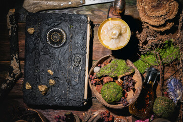 Obraz na płótnie Canvas Concept of magic book, dry herb and magic potion on the wooden table background.
