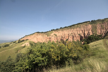 Slopes of Rapa Rosie, the grand canyon of Romania, with orange rocks and green meadows