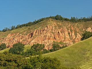 Slopes of Rapa Rosie, the grand canyon of Romania, with orange rocks and green meadows