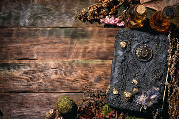 Concept of magic book, dry herb and magic potion on the wooden table background.