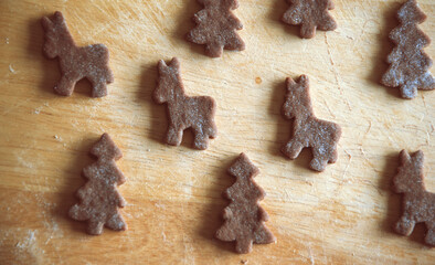 Close up of raw dough for gingerbread cookie on the kitchen table. Baking homemade Christmas cookies. Cutting out a ginger bread x-mas symbols with cutters, Top view. Preparing to celebrate Christmas 