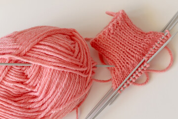 pink wool yarn and knitting needles