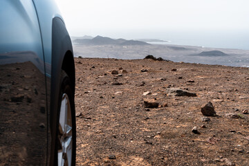 Concept of road trip: car in mountain scenery with ocean background.