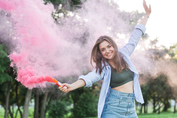 Portrait of a young and attractive Caucasian girl holding colored smoke. Happy, lifestyle