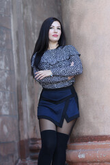 portrait of a girl near the wall. brunette with dark brown eyes. model posing in front of the wall,...