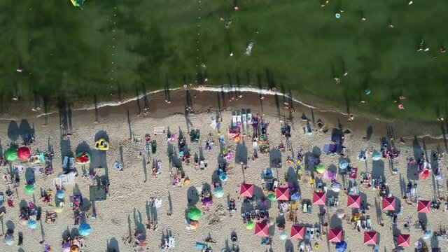 beach of the Zatoka with tourists with sunbeds and umbrellas on the hot summer day
