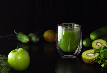 Green smoothie in a glass glass on a black background. Kiwi, apples,cucumbers and greens. Cooking healthy food.