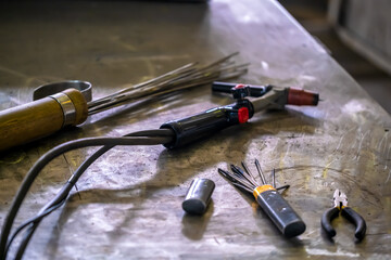 TIG welding. The workplace of the welder, welding equipment on a metal table. Welding torch,...