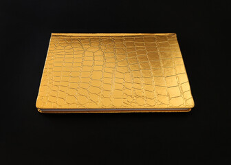 gold crocodile leather diary isolated on black background