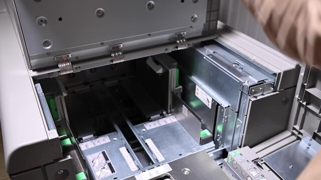 The man opens the cover of the printer to print on paper and cardboard to load paper. Close-up