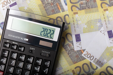 Calculator, euro banknotes and 2022 new year lettering. 2022 tax time. economy background.
