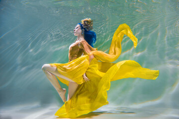beautiful girl with hair in a beautiful bright dress underwater