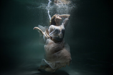 blonde underwater in a white dress