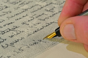 Close-up of a male hand ready to write with an elegant fountain pen. Hand writing letter with...