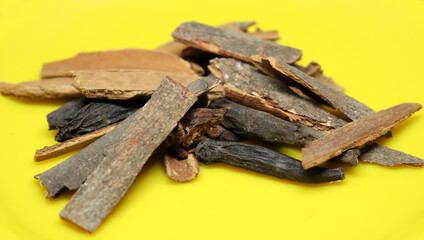 The pile of cinnamon is on a black background on a yellow plate