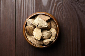 Fototapeta na wymiar Brazil nuts or Bertholletia excelsa seeds in bowl on wooden table