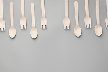 Wooden spoon, fork, paper cups gray background. Disposable tableware made of natural materials. The concept of a zero waste, sustainable lifestyle. Eco-friendly disposable tableware