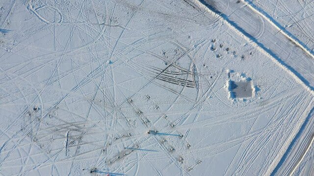 High aerial drone view filming straight down accross tracks of all kind in the white snow covering the frozen river in Berges-des-quatres-vents in Laval-Ouest