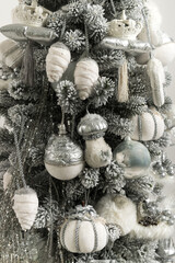 Close up of gray-white Christmas tree with soft toys, and garlands