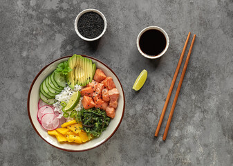 Healthy lunch concept. Organic food: salmon poke bowl with rice, fresh cucumbers, radish, mango, seaweed, and avocado.