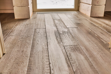 Close-up of natural wood parquet floor room with wooden walls in country house with a door to the street in the background
