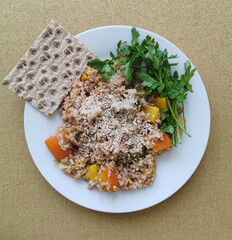 A healthy, balanced breakfast with barley, pumpkin pieces, parsley, sesame, sunflower seeds and one rye wafer