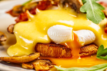 Close-up of eggs Benedict with hollandaise sauce and liquid yolk